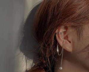 Detail view of silver pearl tassel ear bone clip with long hanging chain on model's ear