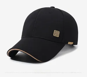 Detail of black baseball cap featuring a golden logo plate and contrast brim piping