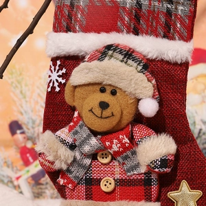 Detail of Christmas stocking with plush bear motif and red grey plaid pattern fabric