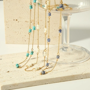 Close-up of golden beaded necklaces with turquoise and cream stones on a stone base