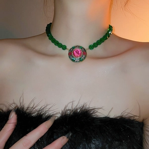 Detail of luxury emerald green bead necklace with ornate gold pendant on neck