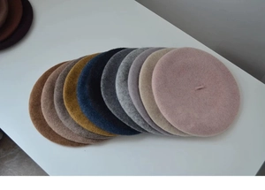 Flat lay showing a diverse palette of thick wool beret hats in multiple stylish colors