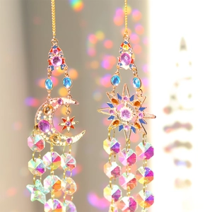 Detail view of asymmetric gold celestial sun and moon pendants with colorful crystals