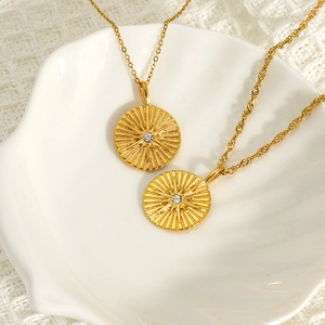 18K gold plated stainless steel sunburst coin pendant necklace for women in a shell dish