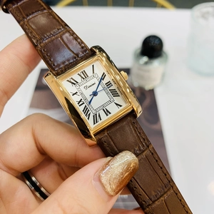Detailed close-up of a rectangular gold quartz watch with a brown leather strap