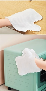 Close-up of white non-woven cleaning gloves wiping wooden and oven surfaces