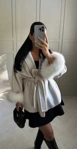Detail of off-white wool coat featuring faux fur cuffs and a waist tie-belt design