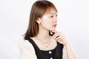 Close-up of layered stainless steel gold heart necklace and stud earrings on model