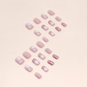 Short matte pink press-on nails with white snowflakes and glittering rhinestone accents