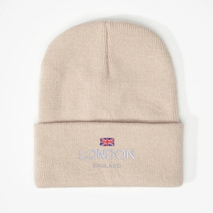 Close-up of oatmeal knit beanie with embroidered UK flag and LONDON ENGLAND lettering