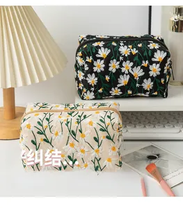 Detail of daisy flower embroidery on black and beige canvas makeup storage bags
