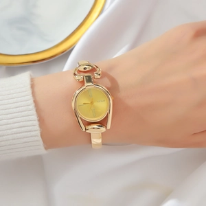 Close-up of a women's vintage gold bangle watch with a sunray dial on silk fabric