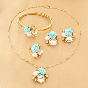 Detailed set of gold-plated jewelry with light blue roses, pearls, and crystals on satin