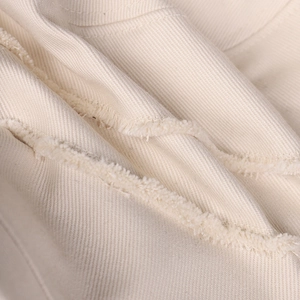 Detailed macro view of off-white twill fabric with decorative raw frayed edges on sun hat