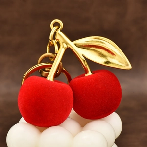 Red flocked cherry keychain with glossy golden metal leaves and a sturdy key ring
