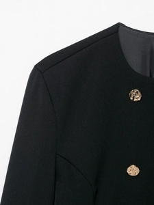 Dettaglio del blazer in twill nero con bottoni in metallo dorato martellato e cuciture