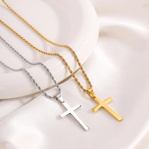 Gold and silver titanium steel cross pendants with rope chains on white silk background