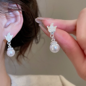 Detail of silver bow earrings with sparkling rhinestones and elegant white pearls