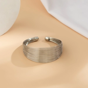 Detail of silver multi-layer wire cuff bracelet with round ends on geometric background