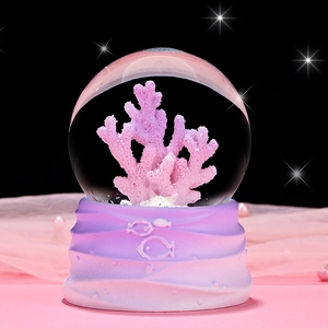 Macro view of ocean crystal ball with pink coral sculpture and decorative gradient base