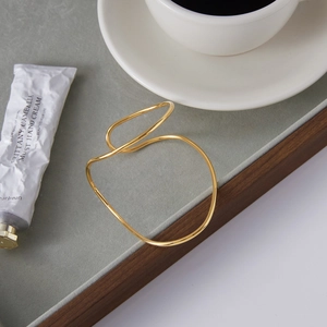 Detailed close-up of golden stainless steel cuff bracelet with high polished curvy finish
