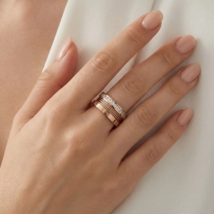 Close-up of stacked rose gold cable rings with Roman numerals and pavé crystals