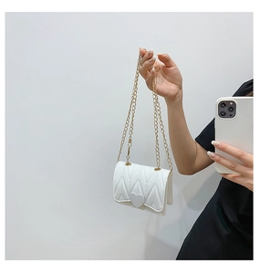Close-up of white mini heart bag with V-quilted faux leather and golden chain strap