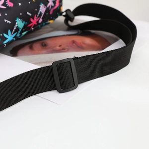Detail of adjustable black nylon shoulder strap with plastic buckle and dinosaur print