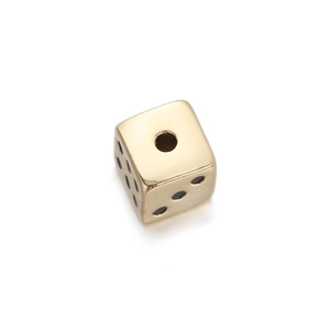Macro shot of gold-plated metal dice bead with central hole and black dots for DIY jewelry