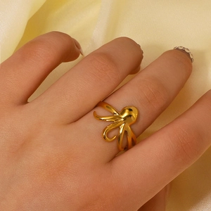 Bague pieuvre minimaliste en acier inoxydable doré sur fond de tissu en soie jaune