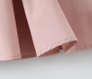 Zoom détaillé sur l'ourlet de la robe rose avec coutures précises et texture fluide