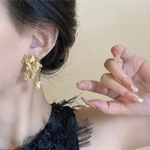 Close-up of golden butterfly fringe earrings worn on model featuring layered aesthetic