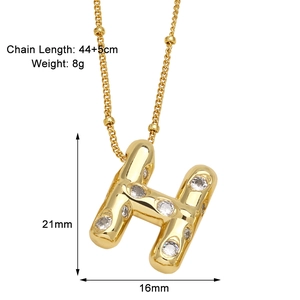Détails macro du pendentif lettre H doré avec pierres de zircone et chaîne perlée