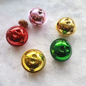 Close-up of colorful 5cm metal Christmas bells with star cutouts on white plush background