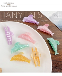 Detail of glitter candy-colored dolphin hair clips displayed on a white ceramic plate