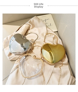 Detailed view of silver, gold, and transparent acrylic heart-shaped clutch bags with chains