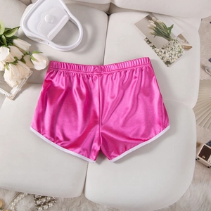 Flat lay of pink satin athletic shorts with white trim and elegant lifestyle accessories