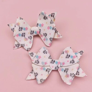 Close-up of white sequined bow hair clips with animal patterns on pink background