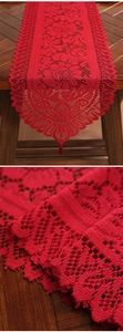 Close-up of red festive lace table runner with intricate hollow-out weaving details