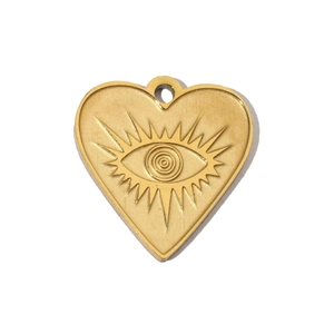 Detailed view of a gold-plated heart pendant with eye and rays engraving on metal