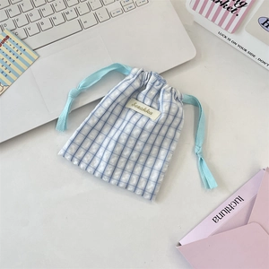 Pochon à cordon en tissu à carreaux bleu et blanc avec étiquette sur bureau