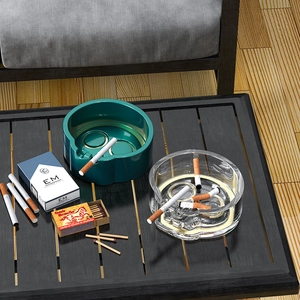 Detail showing skull-shaped ashtrays in dark green and clear glass on a wooden table
