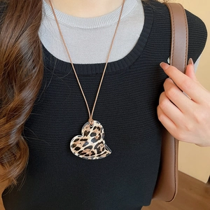 Close-up of model wearing heart leopard print pendant with brown leather cord necklace