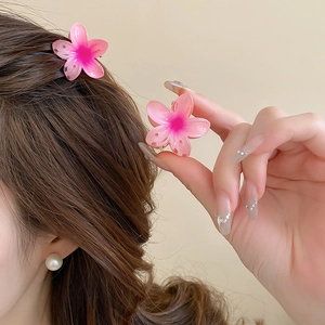 Detail of pink gradient sunflower hair claw clip styled on long brown wavy hair