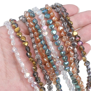 Handheld heart-shaped glass beads in rainbow, gold, and teal colors for DIY jewelry making