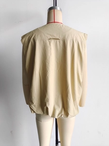 Détail du dos d'un gilet sans manches kaki montrant les coutures et l'ourlet plissé