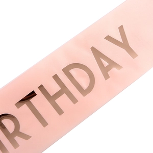 Close-up of pink satin birthday sash with rose gold metallic foil birthday lettering