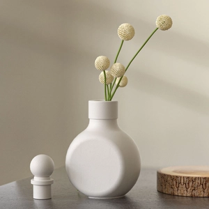 Detailed view of minimalist white resin vase mold with dried flowers on a stone surface