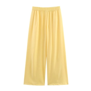 Detail of yellow loose-fit wide-leg trousers with elastic waistband and smooth fabric