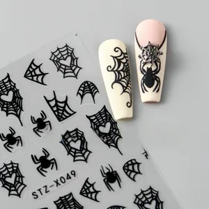Macro shot of Halloween nail art stickers featuring black spider webs and heart spiders